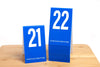 Tall blue table numbers in number sequence 21-40. These tent style table numbers feature a bold white number. Please place at edge of table is printed on the bottom of each number.