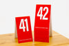 Tall red table numbers in number sequence 41-60. Table numbers feature a bold white number. Please place at edge of table is printed on the bottom of each number. www.citygrafx.com.